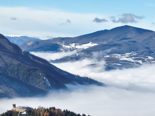 A stunning landscape featuring majestic snow-capped mountains in the background and a clear blue sky with some scattered white clouds