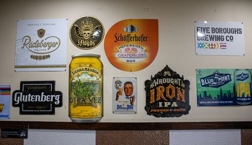 A close-up shot of a wall in an old bar, featuring an eclectic mix of vintage items and signs, including a vintage poster, a light