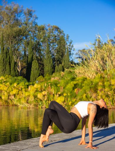 A vertical shot of a brunette Hispanic woman practicing yoga in the morning in a park