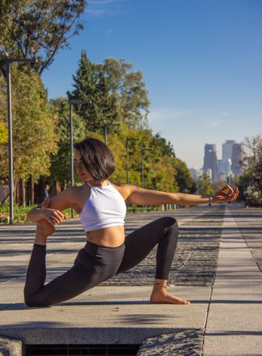 A vertical shot of a brunette Hispanic woman practicing yoga in the morning in a park