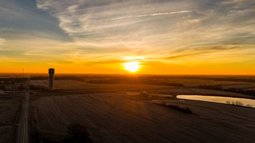 A breathtaking view of a lush green landscape under a vibrant orange sunset sky