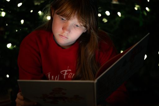 A red-haired girl is looking through a Christmas album