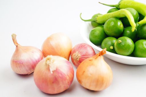 A closeup shot of onion, chili peppers, and thai lemons isolated on a white background