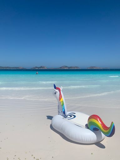 A whimsical inflatable rainbow-colored unicorn floating against a beach backdrop, creating a vibrant and cheerful scene for any project
