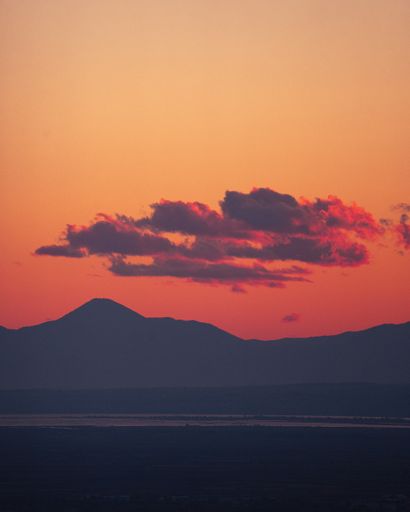 An idyllic landscape of a vibrant sunset sky over rolling mountain peaks