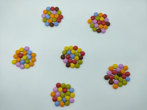 An overhead shot of small colorful candies in collected in six groups