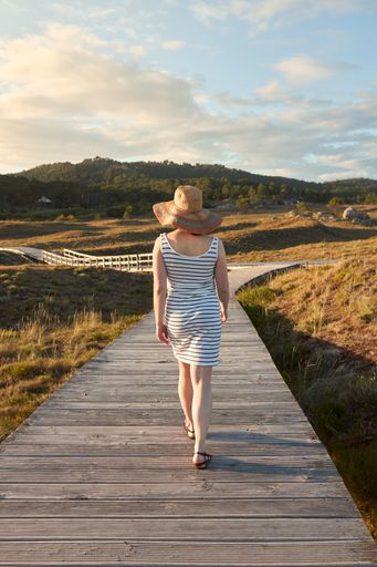 A girl walking along a wooden path to the beach