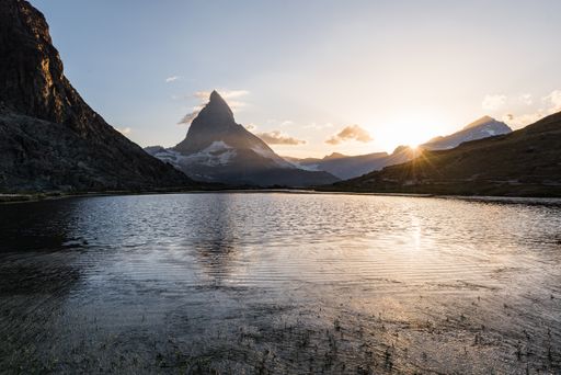 A gorgeous view of Mount. Matterhorn with a golden sun shining behind peaks of mountains