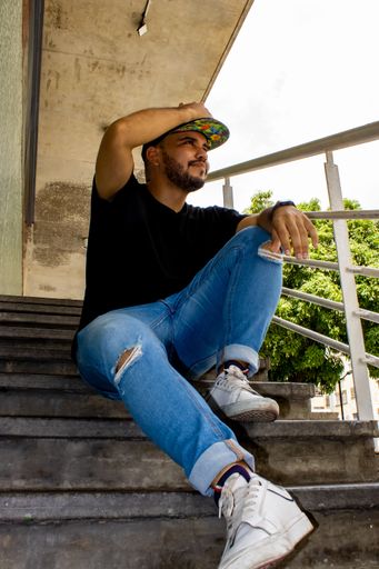 A vertical shot of a young hispanic man sitting on the stairs
