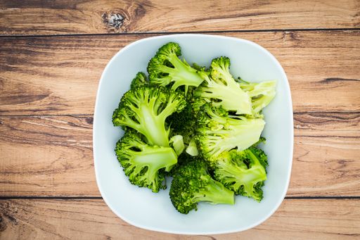 A top view of a plate of green broccoli on a wooden table
