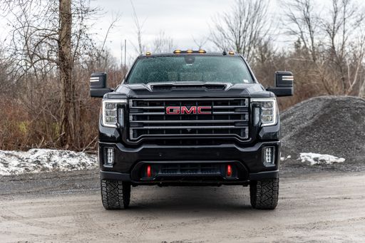 A black GMC truck in a parking area surrounded by trees