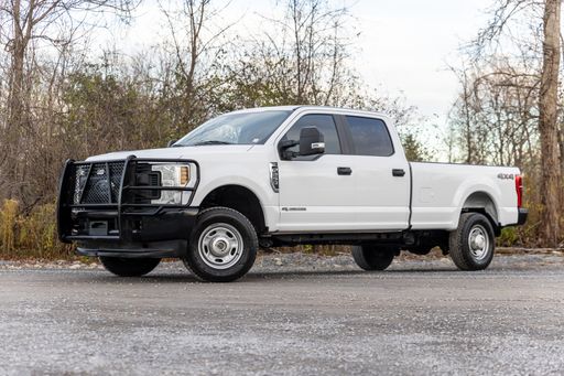 A white Ford pickup truck in a parking area with trees in the background