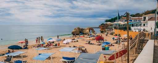 A tranquil beachscape in Algarve, Portugal featuring a sandy beach with turquoise-blue waters.