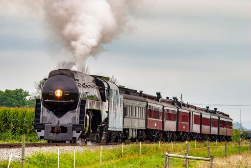 A View of a Steam Passenger Train Approaching, Traveling Thru Rural America, Blowing Smoke on a Summer Day
