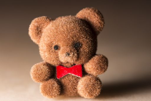 A brown cute teddy bear with a red bow on a brown background