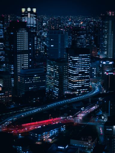 An aerial view of a bustling city illuminated by the bright lights of the tall skyscrapers. Japan