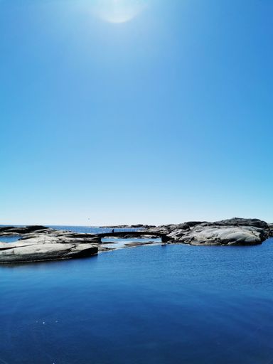 A scenic shot of a sea surrounded by stone mountains in Verdens Ende, Norway