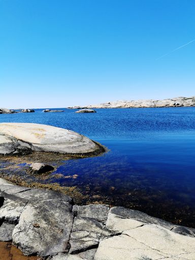 A scenic shot of a sea surrounded by stone mountains in Verdens Ende, Norway