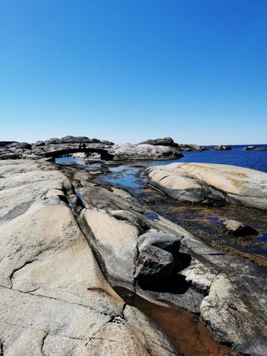 A scenic shot of a sea surrounded by stone mountains in Verdens Ende, Norway