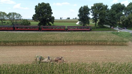 An Aerial View of Six Horses Pulling an Amish Harvesting Corn Stalk Machine, as Steam Passenger Train Passes Thru the Amish Countryside in Autumn