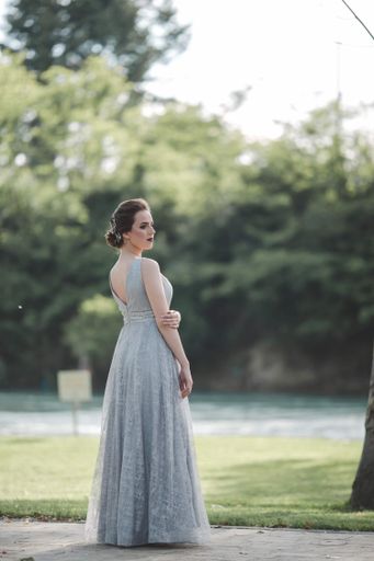 A young attractive Caucasian female with makeup wearing a beautiful evening gown and posing outdoors