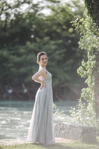 A young attractive Caucasian female with makeup wearing a beautiful evening gown posing near a lake