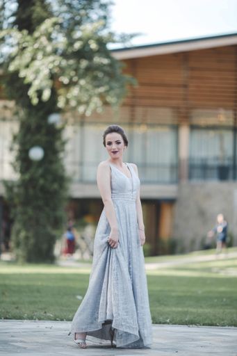 A young attractive Caucasian female with makeup wearing a beautiful evening gown and posing outdoors