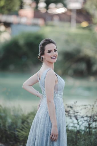 A young attractive Caucasian female with makeup wearing a beautiful evening gown and posing outdoors