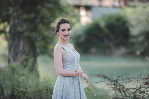 A young attractive Caucasian female with makeup wearing a beautiful evening gown and posing outdoors