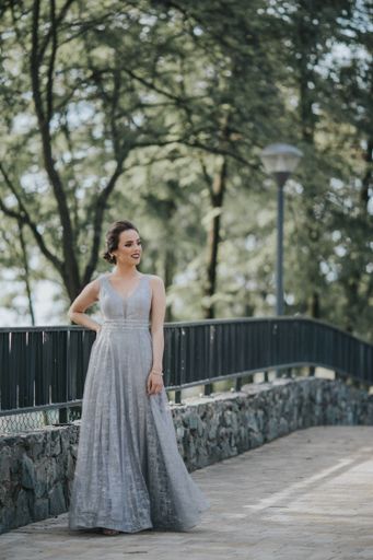 A young attractive Caucasian female with makeup wearing a beautiful evening gown posing on a bridge