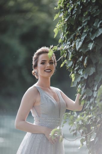 A young attractive Caucasian female with makeup wearing a beautiful evening gown and posing outdoors