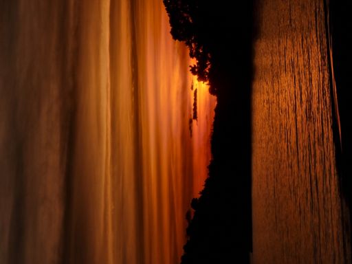 A breathtaking sunset is seen over the horizon of the ocean with a large vessel sailing in the scenic background