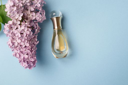 Dior perfume on the light blue background with flowers and leaves. Beautiful design and feminine fragrance for women.