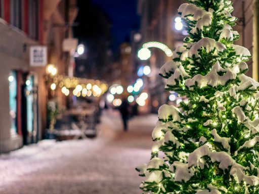 A festive, illuminated Christmas tree standing in the middle of a city street