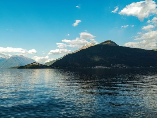 A beautiful scenery of a calm lake surrounded by hills under the cloudy sky