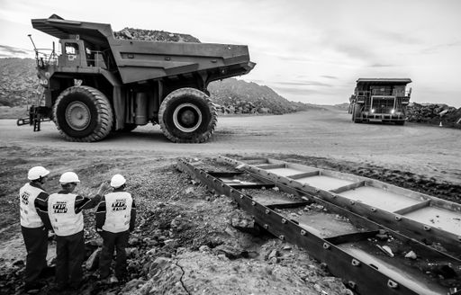 Rustenburg, South Africa, October 15, 2012, Large Dump Trucks transporting Platinum ore for processing with mining safety inspectors in the foreground