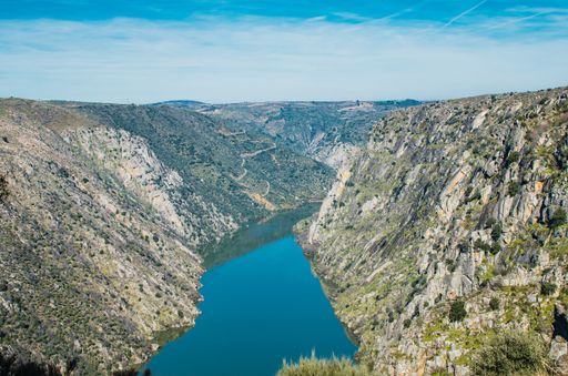 The Duero River surrounded by rocks covered in greenery under the sunlight in Europe