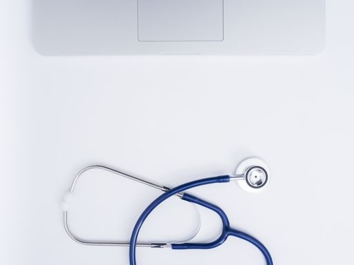 A top view of a medical stethoscope and laptop on a white background with copy space