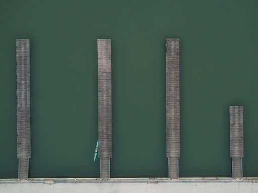 An aerial shot of wooden piers with a small boat in rowing channel