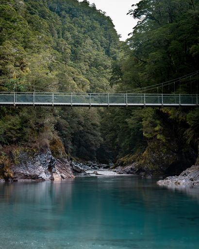 A vertical of Blue pools New Zealand with a rope bridge over the lake