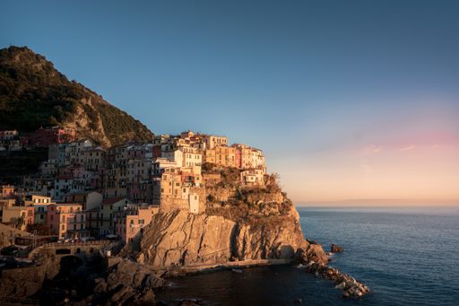 An aerial view of a picturesque village situated atop a cliff, overlooking the glittering expanse of the seas and oceans below
