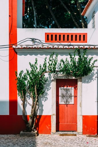 A vertical shot of a red-white house wi8th a small tree in Cascais, Portugal