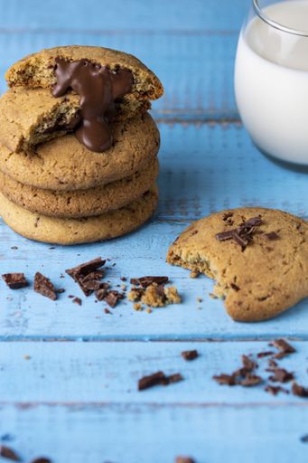 A vertical shot of delicious cookies with yummy chocolate filling and a cup of mil