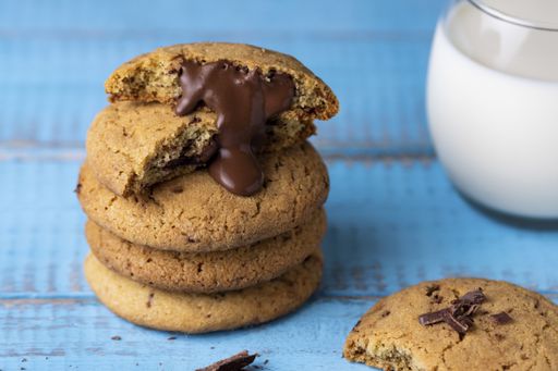 A closeup shot of delicious cookies with yummy chocolate filling and a cup of milk