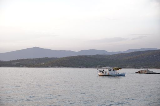A small boat sailing on a peaceful body of water with mountains in the background