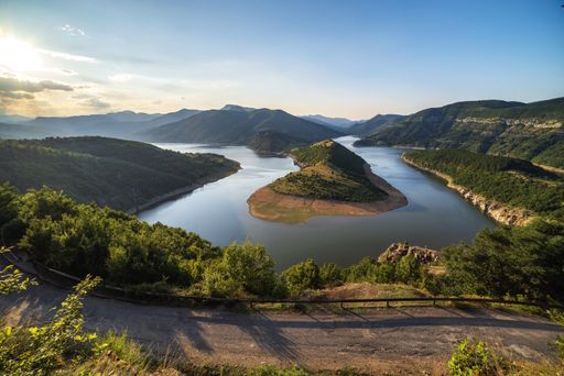 An aerial shot of the river flowing amount the mountains and hills during sunset
