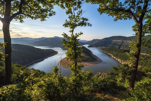 A top view shot of a river flowing between the mountainous valley