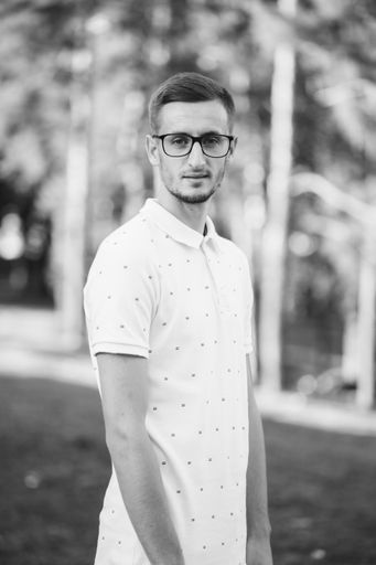 A grayscale shot of a handsome guy in glasses outdoor