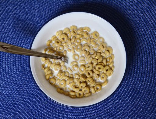 A top view of cereal with milk in the bowl on the blue surface
