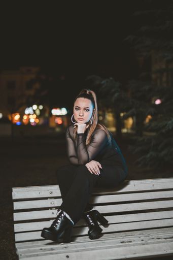 A young attractive Caucasian girl sitting and posing outside in the evening